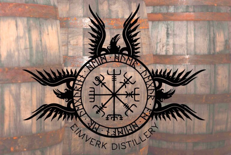 Emblème d’Eimverk Distillery avec runes nordiques sur fond de fûts de whisky en boisCette image montre l’emblème d’Eimverk Distillery, la distillerie islandaise derrière Flóki, superposé à un fond de fûts de maturation en bois. Le motif circulaire, les runes et les ailes stylisées renforcent l’identité visuelle nordique de la maison, tandis que les barriques en arrière-plan rappellent son travail autour du single malt islandais. Une illustration idéale pour accompagner une fiche distillerie, un article consacré à Flóki ou un contenu sur l’émergence du whisky en Emblème d’Eimverk Distillery avec runes nordiques sur fond de fûts de whisky en bois