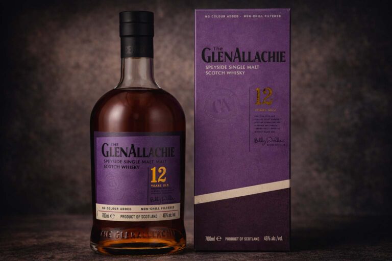 Bouteille de The GlenAllachie 12 ans accompagnée de son étui violet, photographiées sur une surface sombre avec un fond texturé discret.