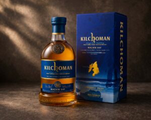 Bouteille de Kilchoman Machir Bay accompagnée de son étui bleu, sur une surface sombre avec un fond texturé sobre.