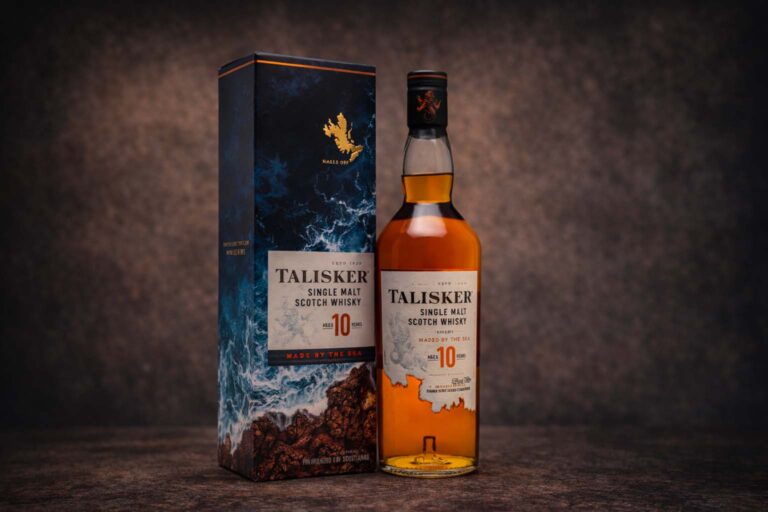 Bouteille de Talisker 10 ans accompagnée de son étui bleu, photographiées sur une surface sombre avec un fond texturé discret.